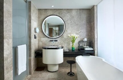 Sofitel Beijing Central gay-friendly hotel bathroom. Modern design with round mirror, sleek sink, and bathtub. Upscale travel for gay men.