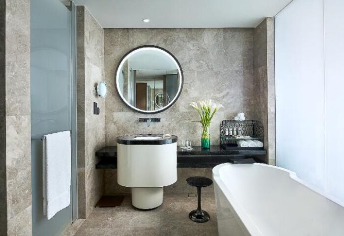 Sofitel Beijing Central gay-friendly hotel bathroom. Modern design with round mirror, sleek sink, and bathtub. Upscale travel for gay men.