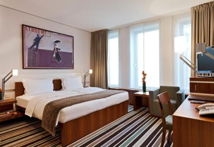 Dorint Kurfurstendamm Hotel room. Gay-friendly hotel, pet-friendly. Modern design, large bed, desk, chair, and artwork. Berlin hotel.