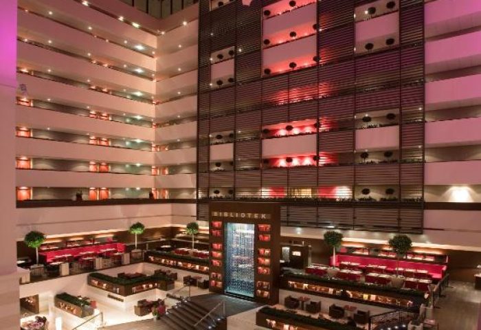 Sofitel Budapest Hotel lobby. A multi-story atrium with a plane hanging from the ceiling, the Bibliotek bar, and lounge areas. Gay-friendly hotel.