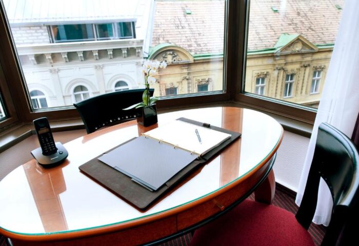 Desk with city view at Sofitel Budapest Hotel, a gay-friendly and pet-friendly hotel. Phone, notepad, pen and orchid on the desk.