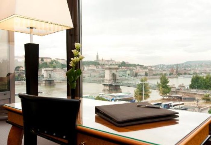 Sofitel Budapest Hotel desk with city view. Gay-friendly, pet-friendly hotel. Room interior with lamp, notebook, and view of the Danube and bridge.