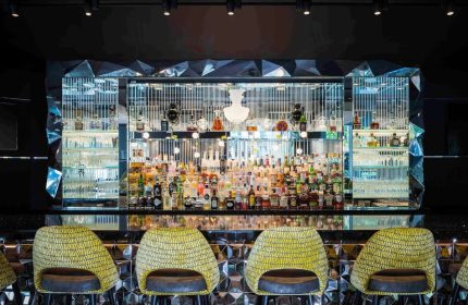 Sofitel Chicago Magnificent Mile gay-friendly hotel bar. Stylish interior with bottles, glasses, and yellow bar stools. Great for gay travel.