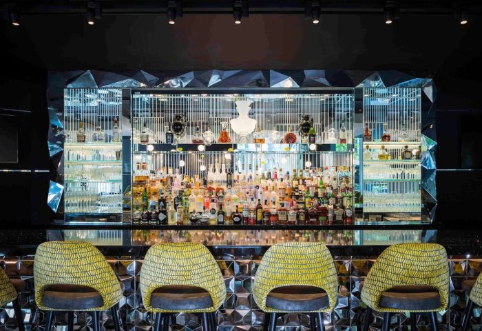 Sofitel Chicago Magnificent Mile gay-friendly hotel bar. Stylish interior with bottles, glasses, and yellow bar stools. Great for gay travel.