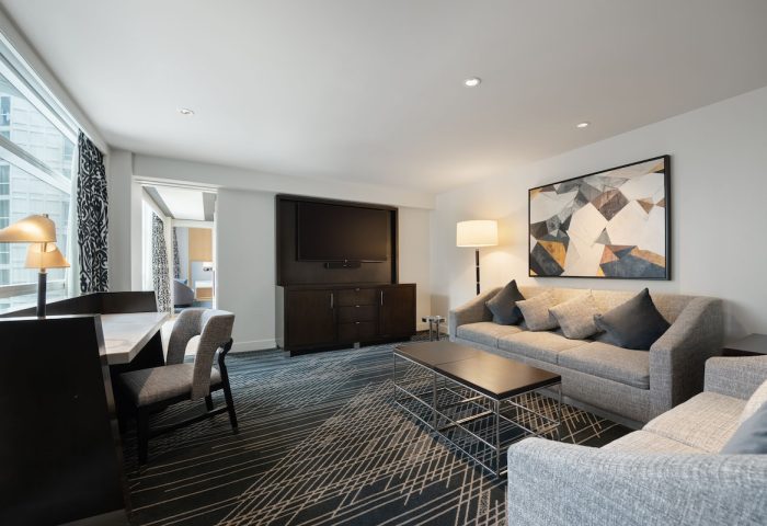 Sofitel Chicago Magnificent Mile gay-friendly hotel suite. Living area with sofa, desk, and TV. Upscale lodging for gay travelers.