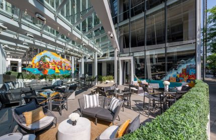 Sofitel Chicago Magnificent Mile's gay-friendly hotel outdoor patio with modern furniture, colorful murals, and glass ceiling.