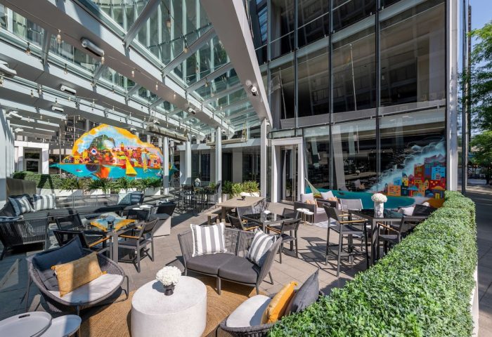Sofitel Chicago Magnificent Mile's gay-friendly hotel outdoor patio with modern furniture, colorful murals, and glass ceiling.