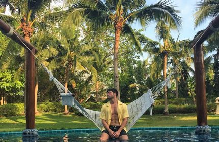 Gay man relaxing in a hammock at Sofitel Krabi Phokeethra Golf and Spa Resort pool. Gay-Friendly hotel in Krabi, Thailand.