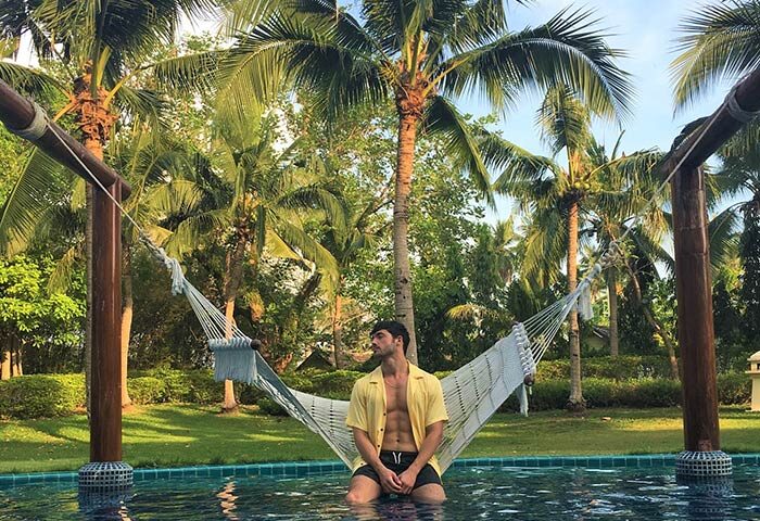 Gay man relaxing in a hammock at Sofitel Krabi Phokeethra Golf and Spa Resort pool. Gay-Friendly hotel in Krabi, Thailand.