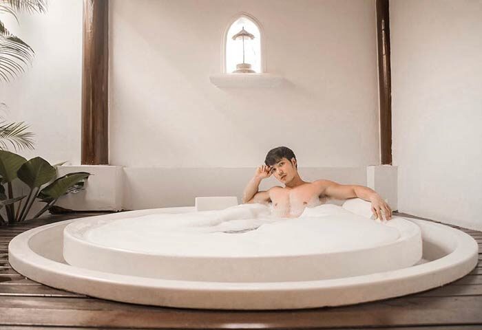 Gay-friendly Sofitel Krabi Phokeethra Golf & Spa Resort: Man relaxing in a bubble bath. Luxury travel experience in Thailand.