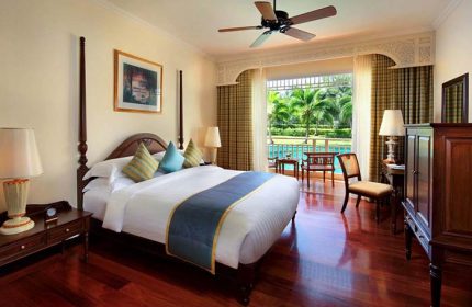 Sofitel Krabi Phokeethra Golf and Spa Resort room. Gay-friendly hotel with a bed, ceiling fan, and balcony overlooking the pool and palm trees.