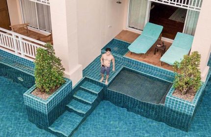Gay-friendly Sofitel Krabi Phokeethra Resort pool view. Man standing by the pool. Luxury travel & relaxation for gay men. Thailand vacation.