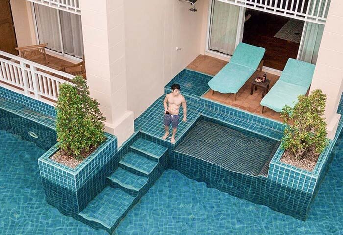 Gay-friendly Sofitel Krabi Phokeethra Resort pool view. Man standing by the pool. Luxury travel & relaxation for gay men. Thailand vacation.