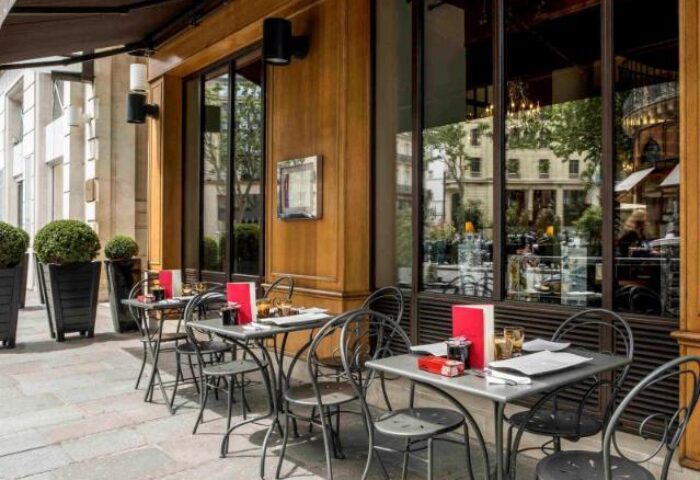 Outdoor seating at Sofitel Le Scribe Paris Opéra, a gay-friendly hotel. Tables are set for dining outside this luxury hotel in Paris.