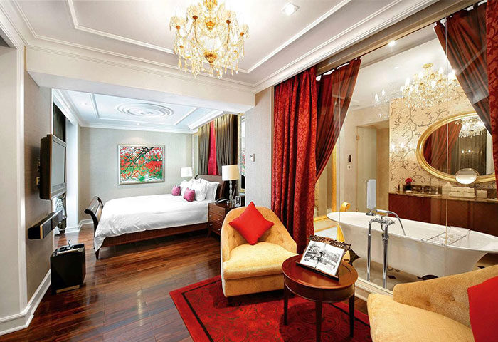 Gay-friendly Sofitel Legend Metropole Hanoi Hotel room. Bedroom with bed, TV, and bathroom with tub. Luxury gay travel in Hanoi, Vietnam.