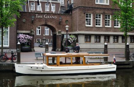Sofitel Legend The Grand Amsterdam: Canal boat at the gay-friendly hotel. A sailor stands on the dock near the boat. Amsterdam travel.