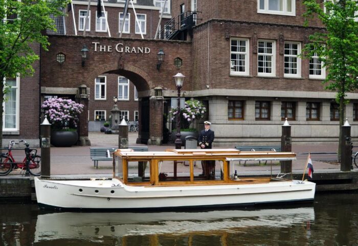 Sofitel Legend The Grand Amsterdam: Canal boat at the gay-friendly hotel. A sailor stands on the dock near the boat. Amsterdam travel.