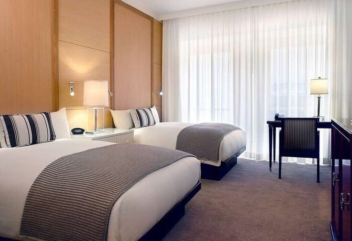 Sofitel Los Angeles at Beverly Hills Hotel: Gay-friendly hotel room with two beds, desk, chair, and striped pillows. Modern design.