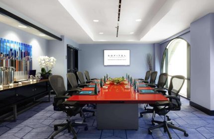Sofitel Los Angeles at Beverly Hills Hotel conference room. Red table, office chairs, and blue carpet. Gay-friendly hotel meeting space.
