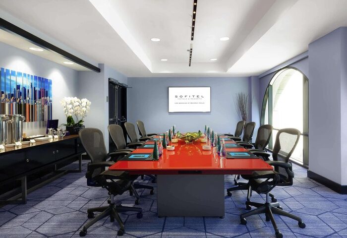 Sofitel Los Angeles at Beverly Hills Hotel conference room. Red table, office chairs, and blue carpet. Gay-friendly hotel meeting space.