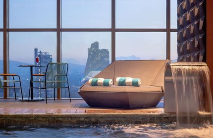 Gay-friendly Sofitel Mexico City Reforma hotel pool area. Lounge chair, waterfall feature, and city view. Relaxing space for gay travelers.