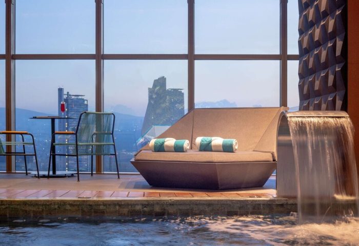 Gay-friendly Sofitel Mexico City Reforma hotel pool area. Lounge chair, waterfall feature, and city view. Relaxing space for gay travelers.
