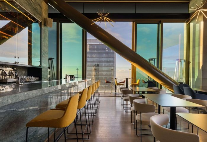 Sofitel Mexico City Reforma's gay-friendly bar. Modern interior with city views, bar stools, tables, and unique architectural details.