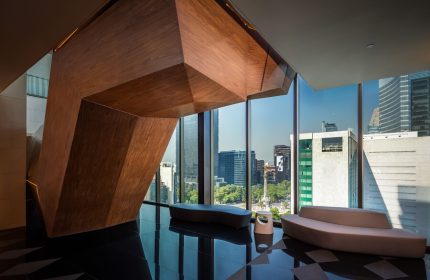 Sofitel Mexico City Reforma interior. Modern design, wood sculpture, sleek benches, and city view. Gay-friendly hotel for sophisticated travelers.
