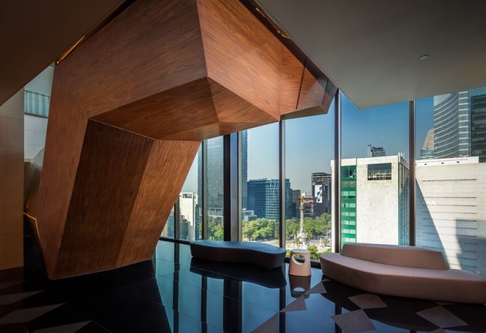 Sofitel Mexico City Reforma interior. Modern design, wood sculpture, sleek benches, and city view. Gay-friendly hotel for sophisticated travelers.