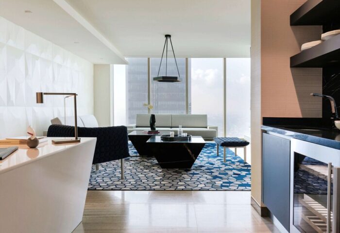 Sofitel Mexico City Reforma suite. Gay-friendly hotel living room with modern decor, blue rug, and city view. Luxury travel in Mexico City.