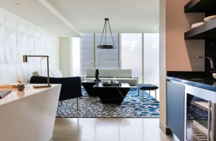 Sofitel Mexico City Reforma suite. Gay-friendly hotel living room with modern decor, blue rug, and city view. Luxury travel in Mexico City.
