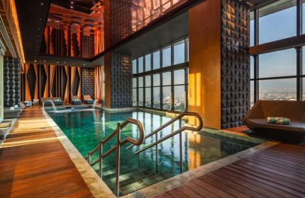 Indoor pool with city views at the gay-friendly Sofitel Mexico City Reforma hotel. Wood floors, lounge chairs, and modern design.