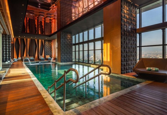 Indoor pool with city views at the gay-friendly Sofitel Mexico City Reforma hotel. Wood floors, lounge chairs, and modern design.