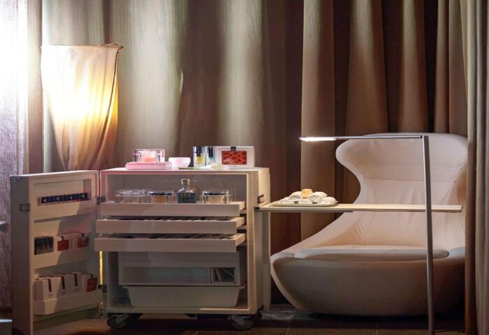 Sofitel Munich Bayerpost Hotel room detail. Gay-friendly hotel with chair, cabinet, and amenities. Luxury travel in Munich, Germany.
