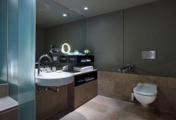 Sofitel Munich Bayerpost Hotel bathroom. Modern design with sink, mirror, and toilet. Gay-friendly hotel.