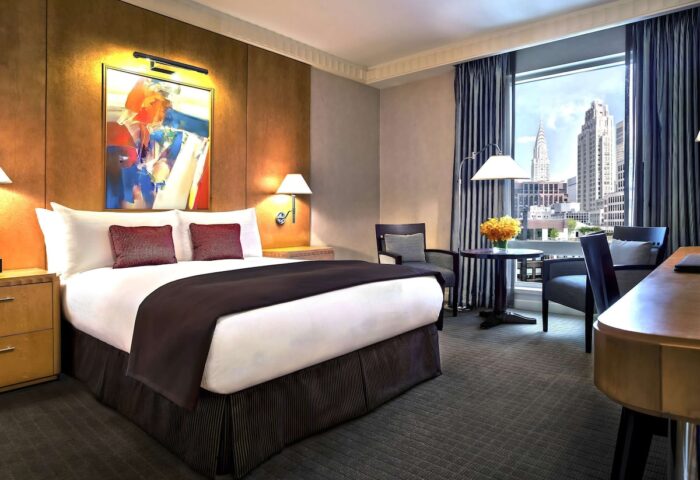 Sofitel New York hotel room. Gay-friendly hotel with a bed, chairs, desk, and a view of the New York City skyline, including the Chrysler Building.