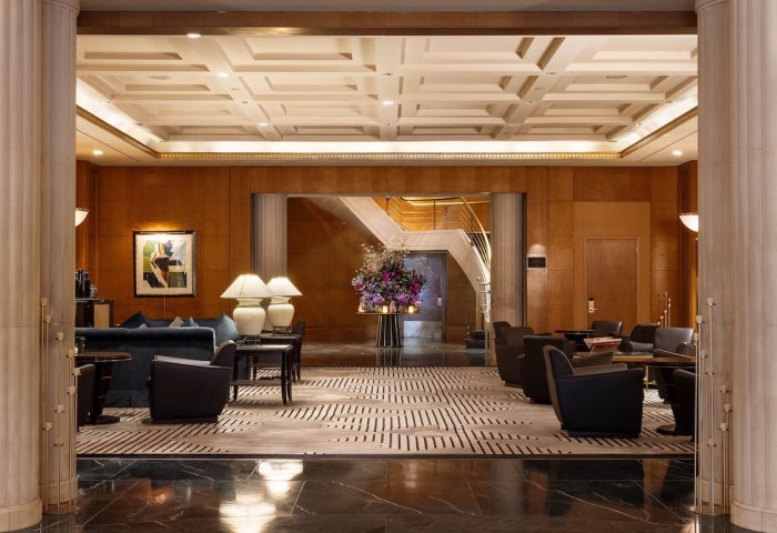 Sofitel New York's lobby. A gay-friendly hotel with stylish seating, a grand staircase, and elegant decor. Perfect for gay men's travel advice.