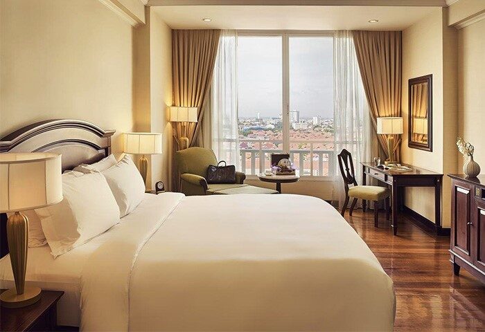 Sofitel Phnom Penh Phokeethra Hotel room. Gay-friendly hotel with a bed, desk, chair, and city view. Luxury accommodations in Phnom Penh.