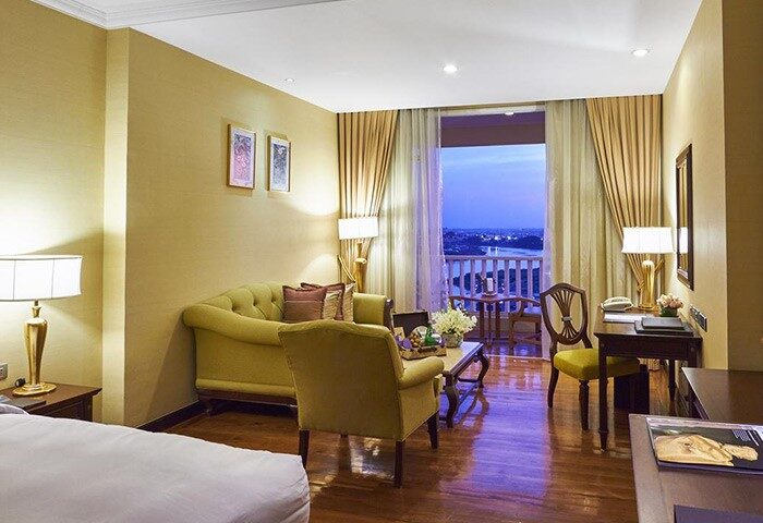 Sofitel Phnom Penh Phokeethra Hotel room. Gay-friendly hotel with balcony view. Elegant interior, seating area, desk. Luxury Phnom Penh stay.