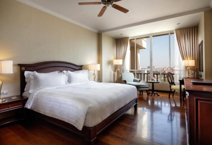 Sofitel Phnom Penh Phokeethra Hotel room. Upscale gay-friendly hotel with king bed, city view, ceiling fan, & wood floors. Luxury Cambodian stay.
