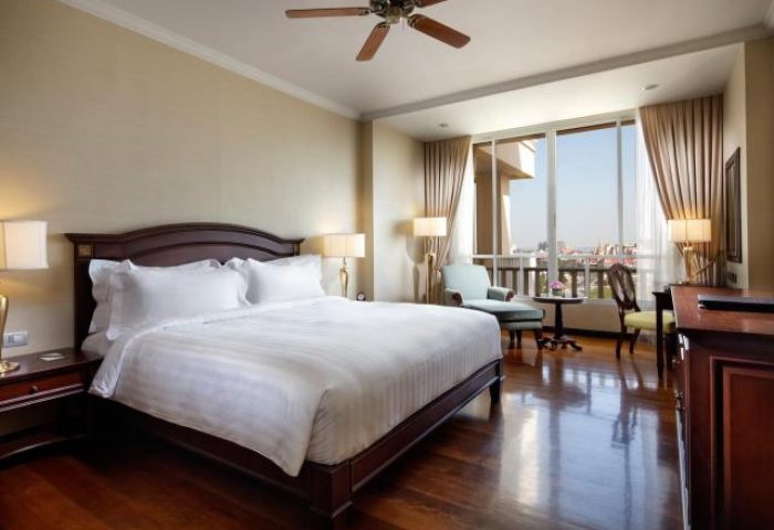 Sofitel Phnom Penh Phokeethra Hotel room. Upscale gay-friendly hotel with king bed, city view, ceiling fan, & wood floors. Luxury Cambodian stay.