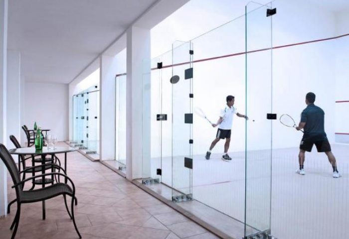 Squash court at Sofitel Phnom Penh Phokeethra Hotel. Two men play squash. Gay-friendly hotel with sports facilities.