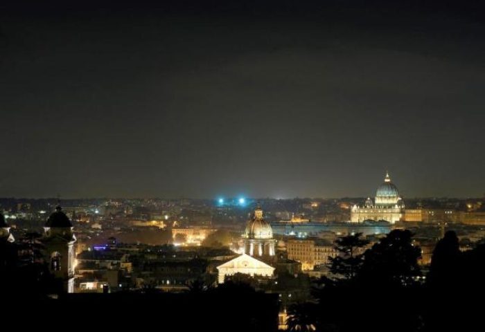 Night view from Sofitel Rome Villa Borghese Hotel, a gay-friendly hotel. Rome skyline with illuminated domes and buildings in the dark.