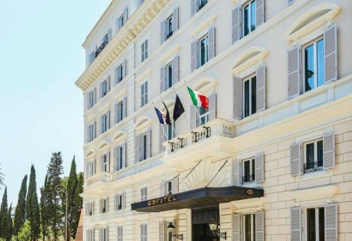 Facade of the Sofitel Rome Villa Borghese Hotel, a gay-friendly hotel in Rome, Italy. Flags waving. Luxury travel for gay men.