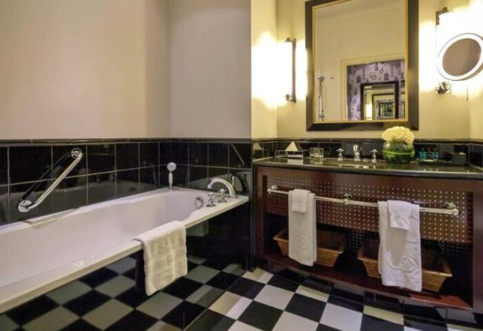 Bathroom at Sofitel St James London Hotel. Pet-friendly, gay-friendly hotel with black and white checkered floor, bathtub, and vanity with mirror.