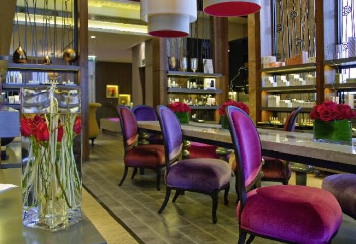 Sofitel St James London Hotel interior. Gay-friendly, pet-friendly hotel. Purple chairs at a long table, flowers, and shelves.