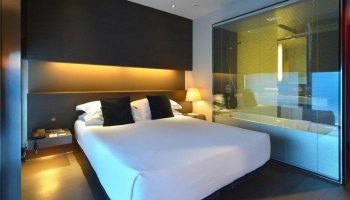 Hotel Soho gay-friendly room. Modern design with a bed, dark headboard, and glass-enclosed bathroom. Perfect for gay men travelers.
