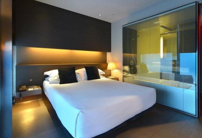 Hotel Soho gay-friendly room. Modern design with a bed, dark headboard, and glass-enclosed bathroom. Perfect for gay men travelers.