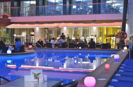 Sol Costablanca Adults-only hotel pool at night. People enjoy music, drinks. Gay-friendly hotel, perfect for gay men travel.