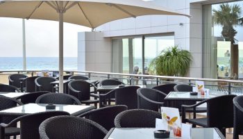 Sol Costablanca Adults-only Hotel: Outdoor terrace with tables, chairs, and ocean view. Gay-friendly hotel in Spain.